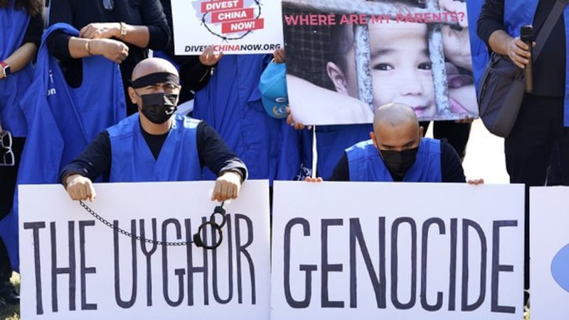 流亡美国的维吾尔人在白宫前抗议示威,他们的标语牌上写着:“(对)维吾尔人的种族屠杀”。(美联社)